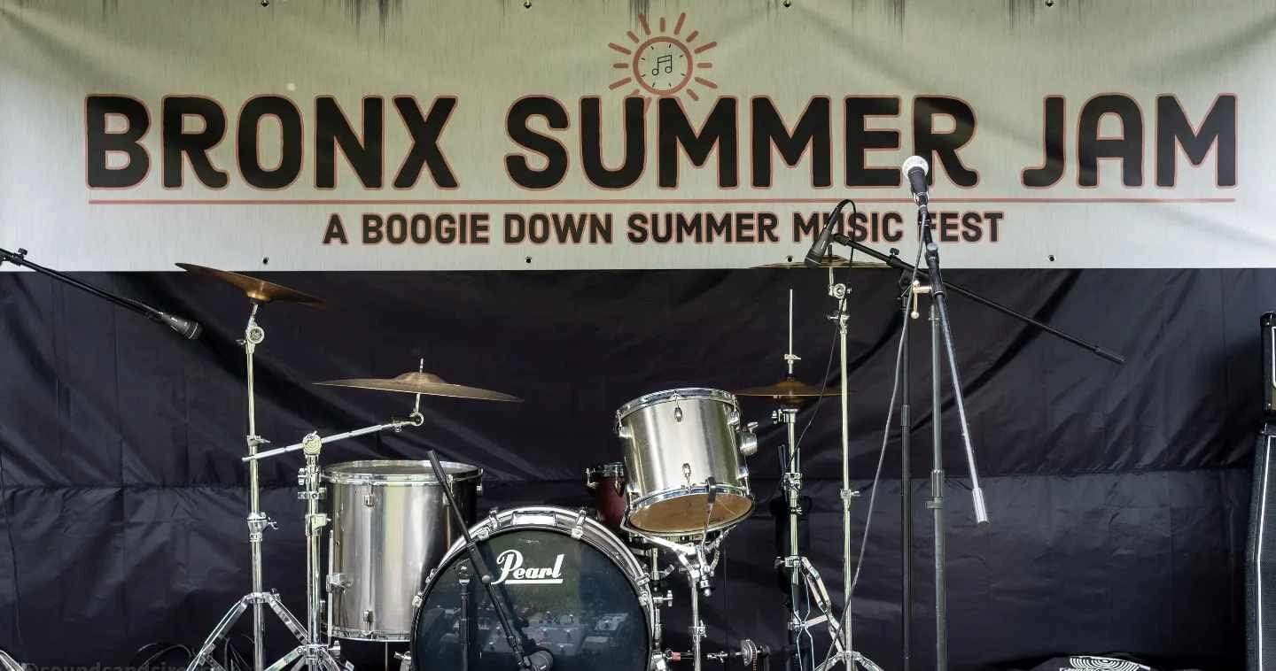 A drum kit on stage beneath a banner reading 'Bronx Summer Jam — A Boogie Down Summer Music Fest.'